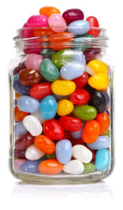 A clear jar with many brightly colored jelly bean candies