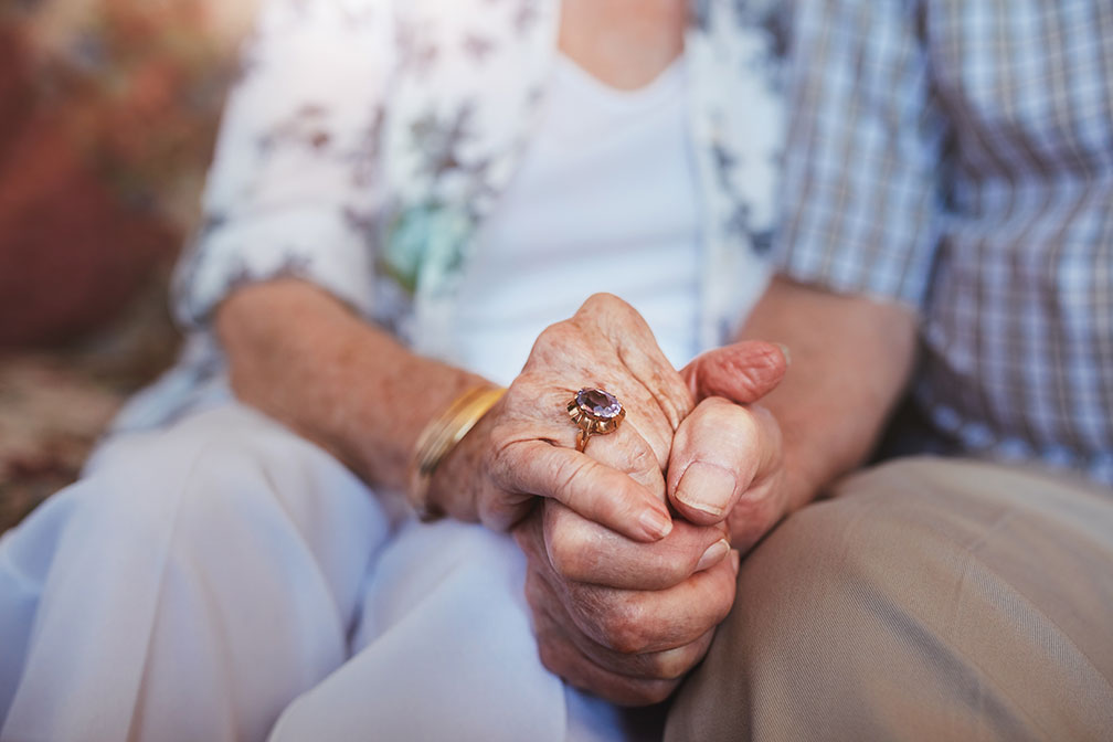 elderly man and woman holding hands